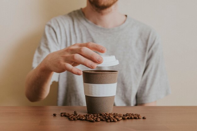 再利用可能なコーヒーカップを開く男