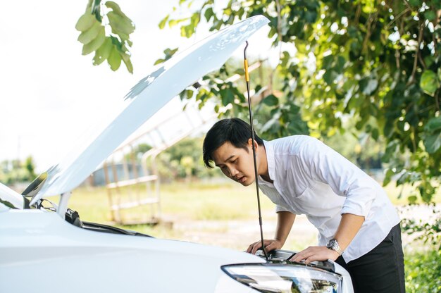 A man opens the hood of a car to repair the car due to a breakdown.