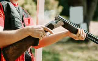 Free photo man opens the shotgun bolt after one shot with smoke