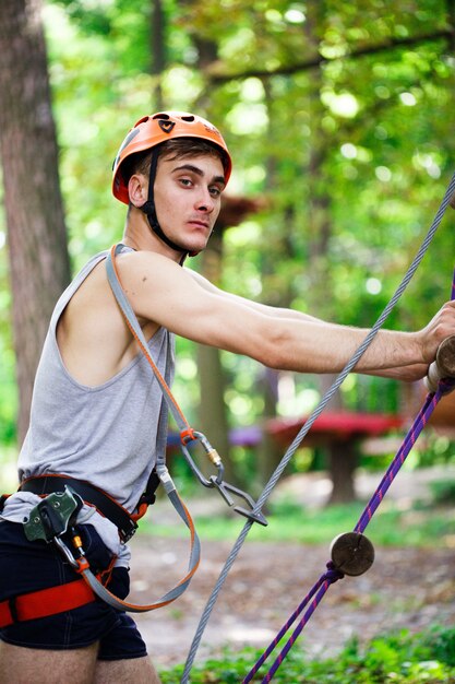 Man in an orange helmet goes up a rope ladder
