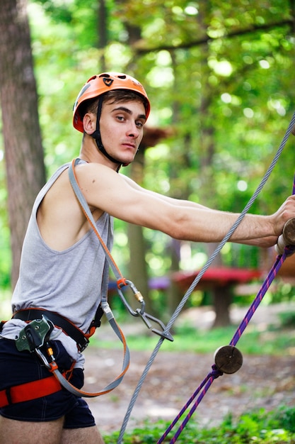 Man in an orange helmet goes up a rope ladder