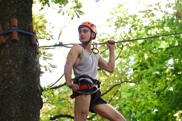 Man in an orange helmet is ready to climb the rope