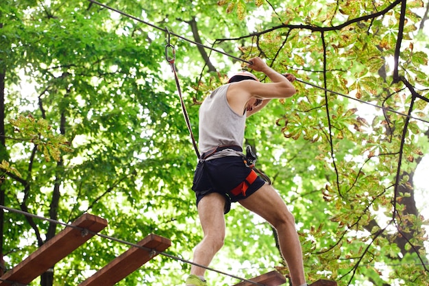 Man in an orange helmet is ready to climb the rope