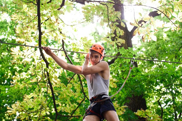 Man in an orange helmet is ready to climb the rope