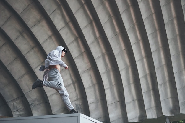 The man outdoors practices parkour, extreme acrobatics.