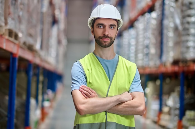 Man in overalls looking at camera with folded hands