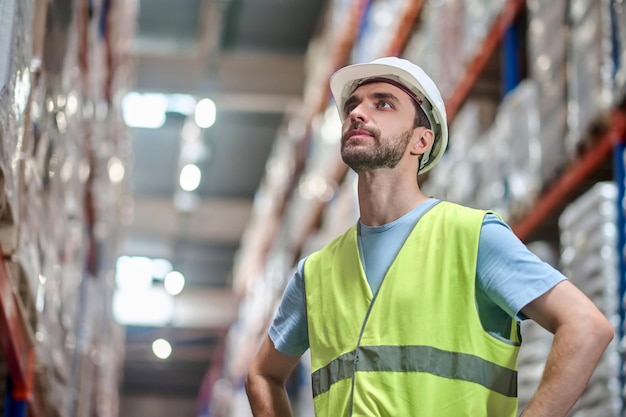 Man in overalls with hands on belt looking up