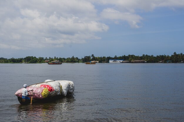 Man paddling a wooden canoe full of plastic