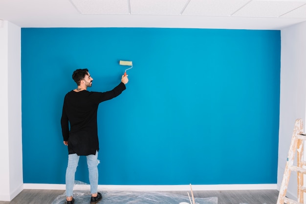 Man painting blue wall