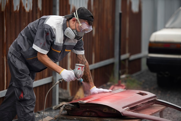 Foto gratuita vista laterale della portiera dell'auto della pittura dell'uomo