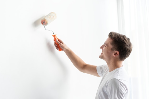 Free photo man painting his wall white