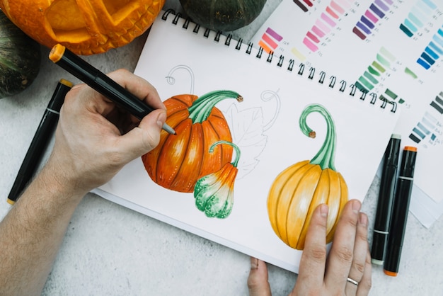 Free photo man painting pumpkin with felt-tip pen