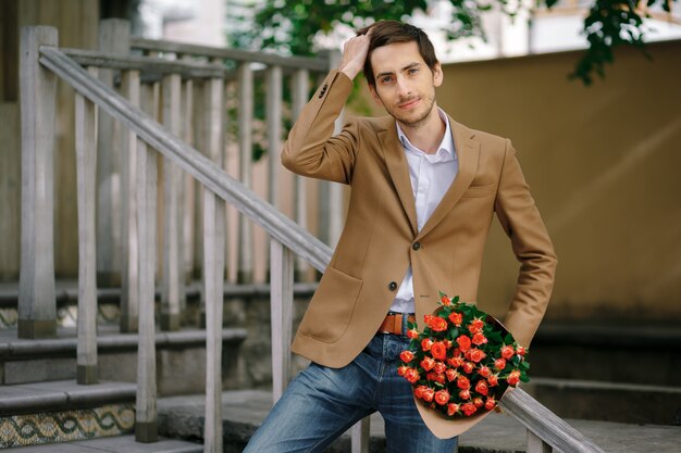 Man passes hand through his hair while holding bunch of roses