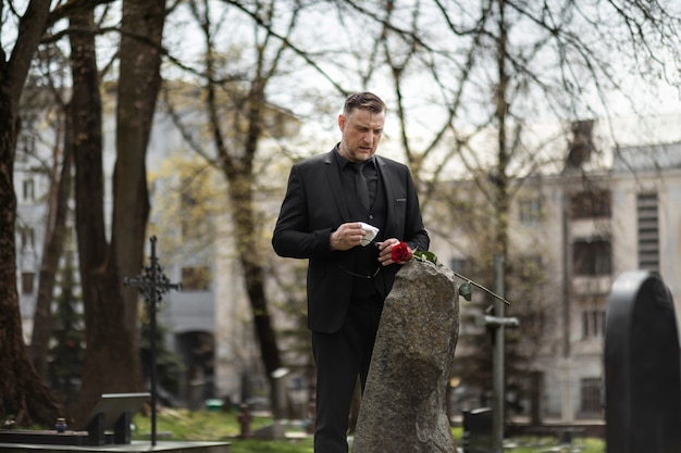 Мужчина отдает дань уважения надгробной плите на кладбище