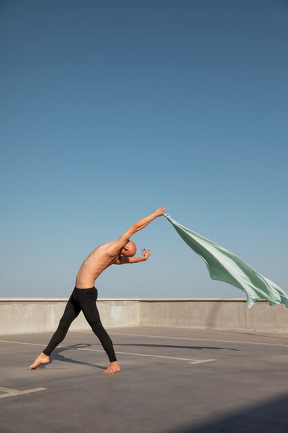 Man performing artistic dance on a rooftop with blue sky