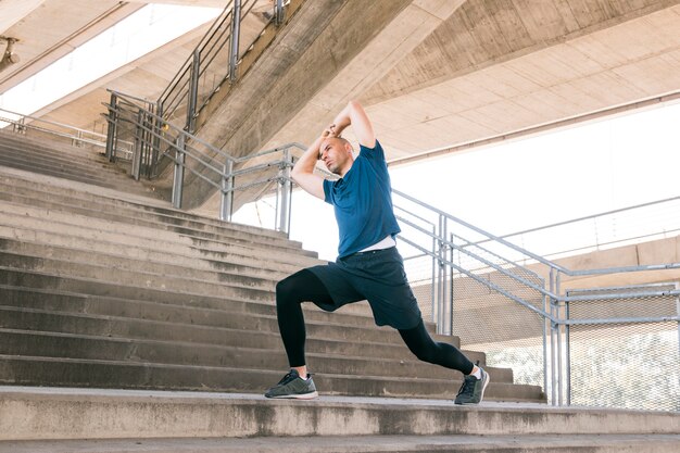 Человек выполняет упражнения на растяжку на бетонных лестницах