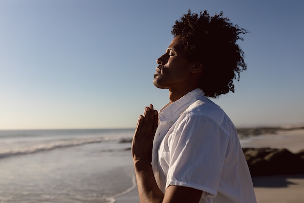 Free photo man performing yoga on the beach