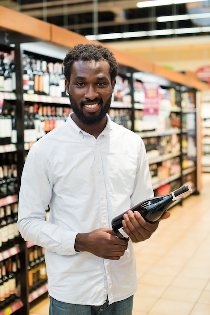 Man picking bottle of wine in alcohol section