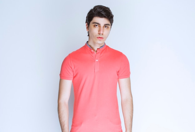 중립 포즈를주는 분홍색 셔츠에있는 남자.