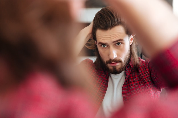 Free photo man in plaid shirt standing and looking at the mirror