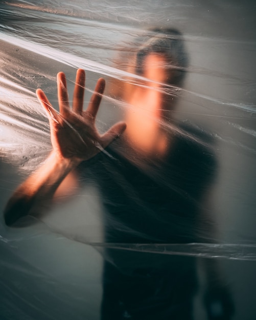 Free photo man behind a plastic bag touching it with his palm