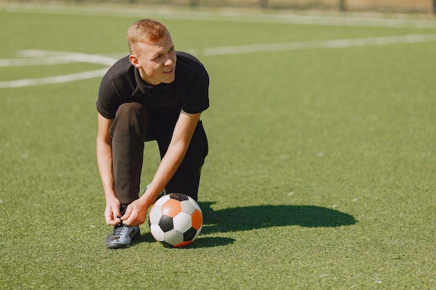 Man play socerl at the park. Tournament on mini-footbal. Guy in a black sportsuits.