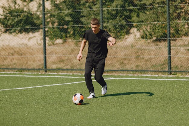 Man play socerl at the park. Tournament on mini-footbal. Guy in a black sportsuits.