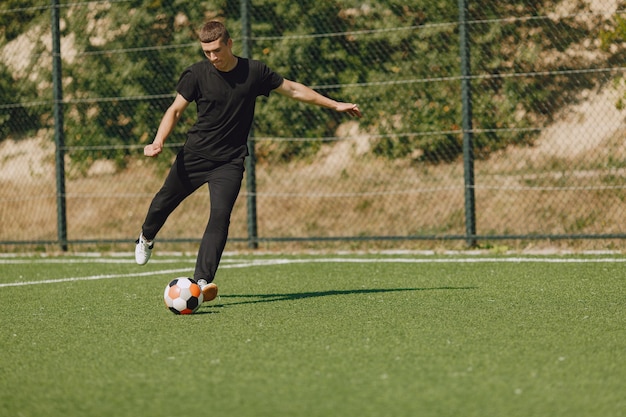 Man play socerl at the park. Tournament on mini-footbal. Guy in a black sportsuits.