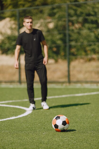 남자는 공원에서 socerl을 재생합니다. 미니 축구 토너먼트. 검은 sportsuits에있는 남자.