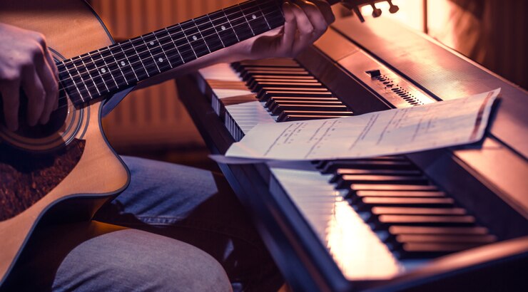 Free Photo man playing acoustic guitar and piano close-up, recording notes, beautiful color background, music activity concept