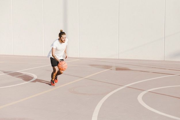 Free photo man playing basketball in court