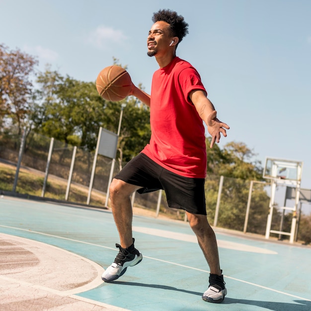 Free photo man playing basketball on a field