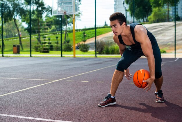 Человек играет в баскетбол на площадке парка