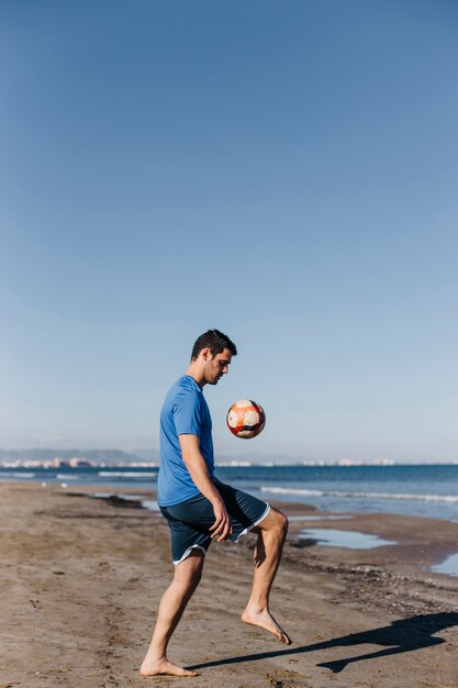 ビーチでサッカーをしている男