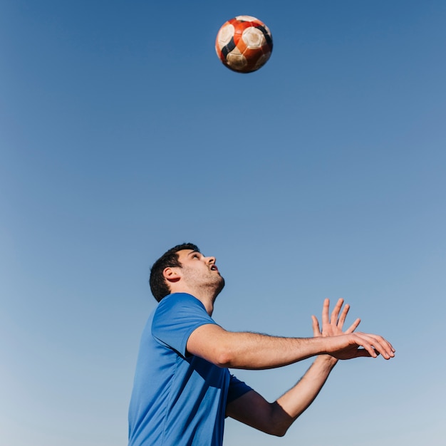 Free photo man playing football at the beach