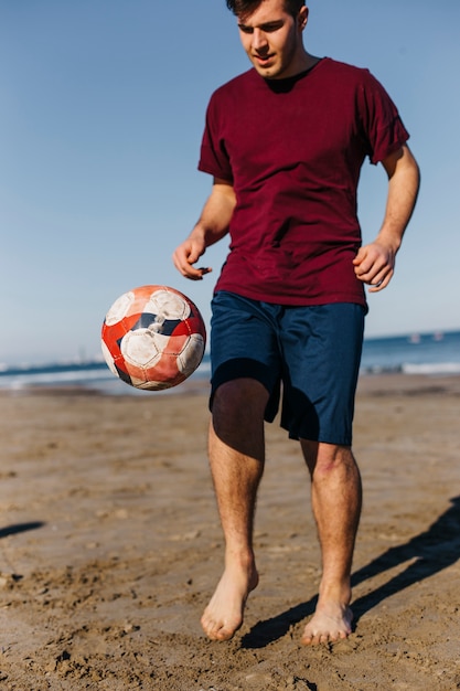 Foto gratuita uomo che gioca a calcio in spiaggia