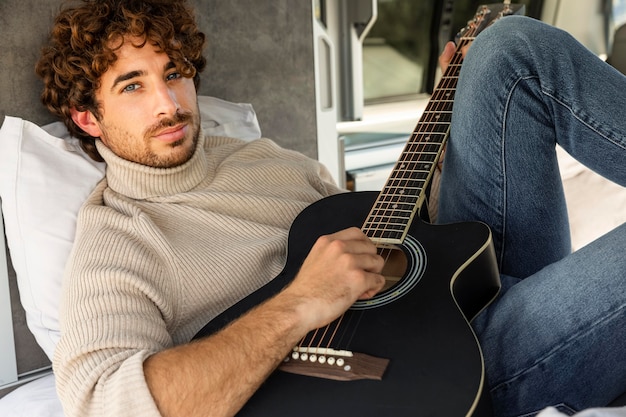 Free photo man playing guitar in his car while on a road trip