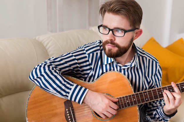 Foto gratuita uomo che suona la chitarra a casa