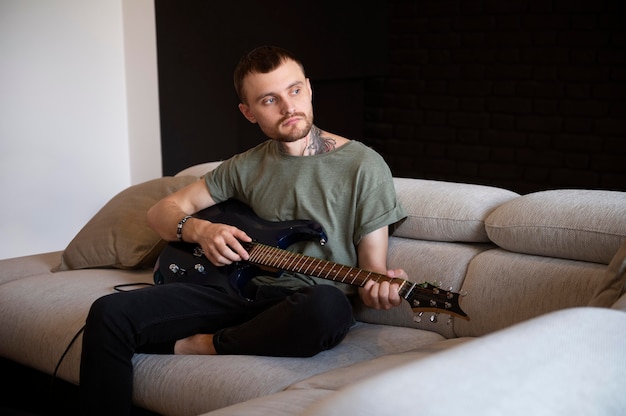 Free photo man playing guitar at home