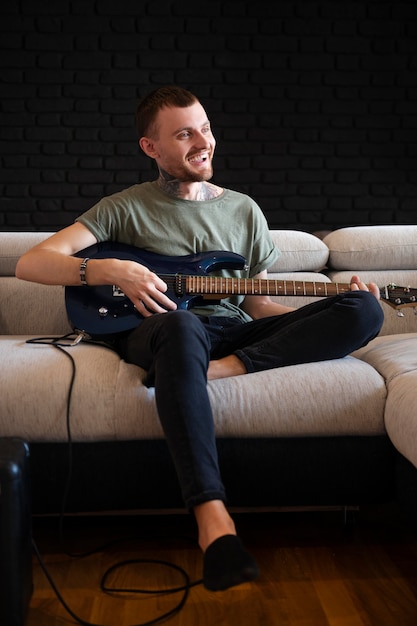 Free photo man playing guitar at home