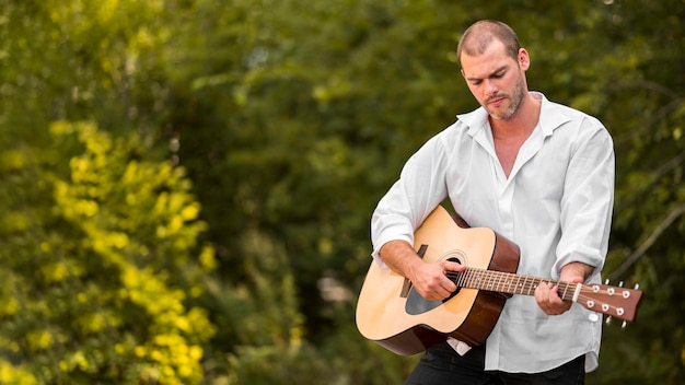 Foto gratuita uomo che suona la chitarra nella natura