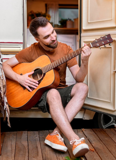彼のバンの外でギターを弾く男