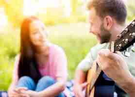 Free photo man playing guitar on picnic