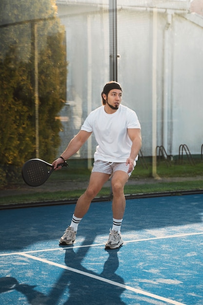 Мужчина играет в паддл-теннис в полный рост