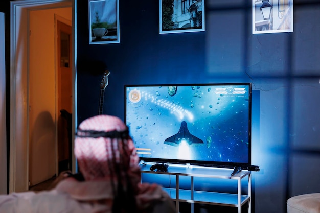 Free photo man playing space shooter game on tv