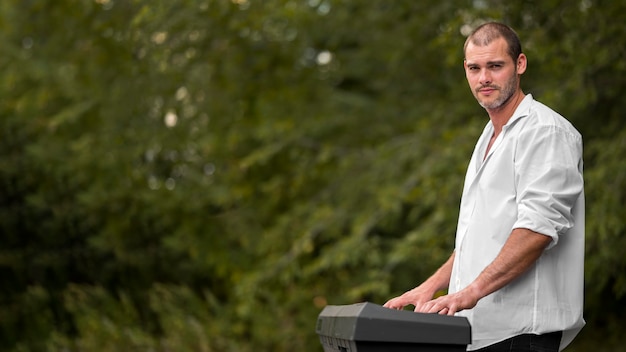 Man playing synthesizer keyboards outdoors copy space