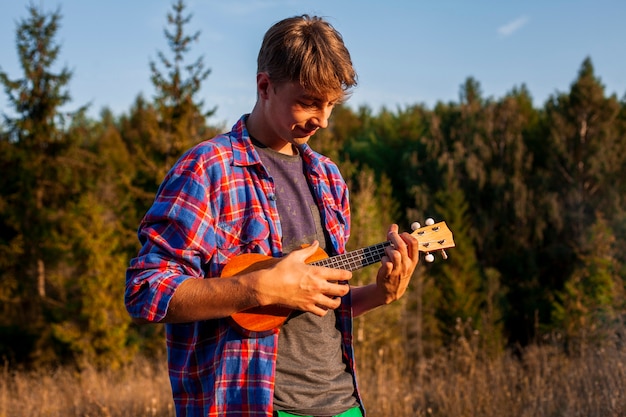 Foto gratuita uomo che gioca ukulele nella foresta