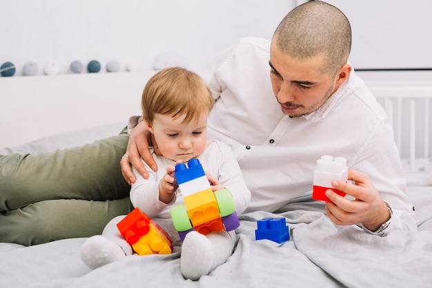 おもちゃのビルディングブロックを保持している小さな赤ちゃんと遊ぶ男