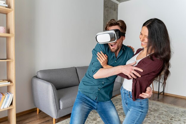 Man playing with virtual reality headset at home next to woman