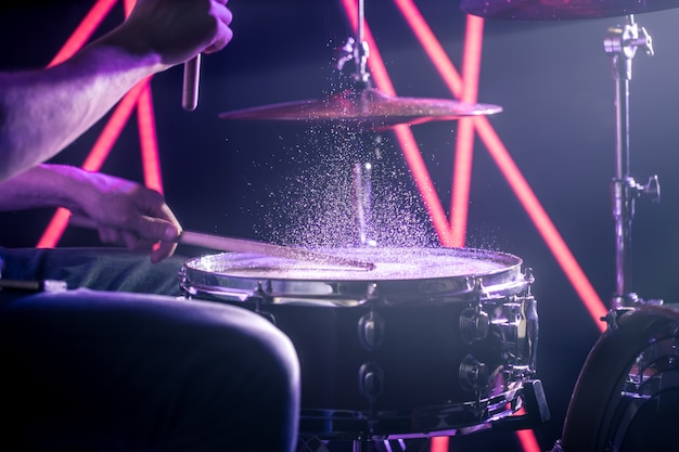 남자는 색깔의 빛의 배경에 드럼을 연주